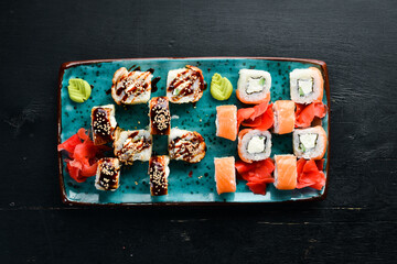 Sushi and rolls on the plate. Top view. Free space for your text. On a black background.