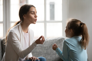 Close up caring mother teaching adorable daughter, working with speech defects and correct...