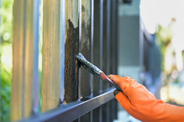 Worker painting steel with paint brush and orange gloves selective focus on hand