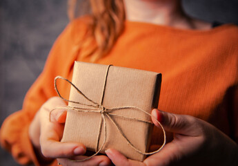 Young Female holding a kraft gift box, wrapped in plain brown paper, Valentines day, Birthday,...
