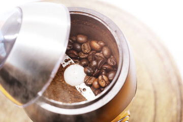 Electric coffee-mill machine with roasted coffee beans on the kitchen table with green tabletop