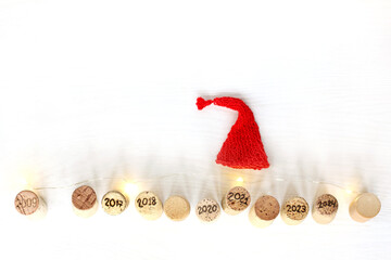 red cap and wine corks with numbers on a table with garland lights top view. festive new year 2021