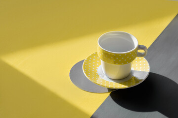 Illuminating Yellow and Ultimate Gray, colors of the year 2021. Yellow ceramic cup on geometric...