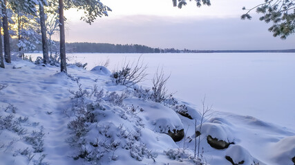 Russia, Karelia, Kostomuksha. The sun illuminates the snow-covered lake. December 18, 2020.