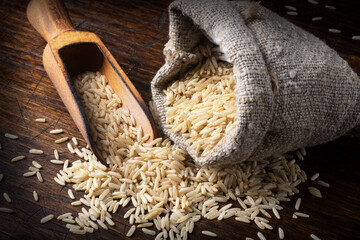 Rice in jute sack bag and in wooden spoon.