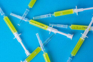 Several syringes with a vaccine on a blue background.