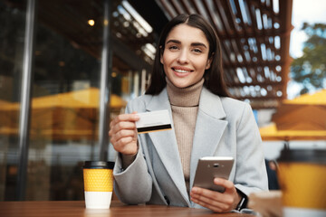 Online payment and shopping concept. Businesswoman sitting in cafe with credit card and mobile phone, purchase something in internet or transfer money