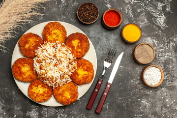 top view fried cutlets with cooked rice and seasonings on dark floor photo food meat dish