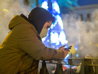 Hombre joven usando su teléfono móvil durante el invierno 
