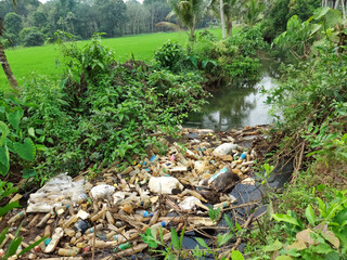 Kerala ,India december17 ,2020 plastic waste and bottles floating in a small river left by careless people near a rice crops field in Kerala India