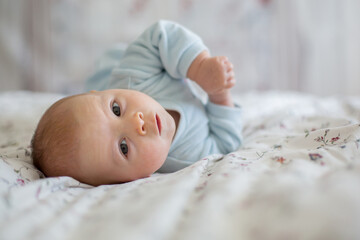 Adorable baby boy in white sunny bedroom in winter morning