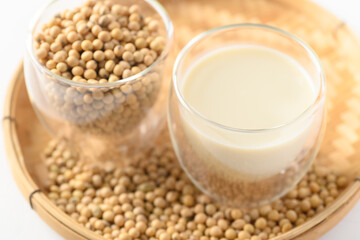 Soy milk and soy beans in a glass on bamboo tray with white background, Healthy drink