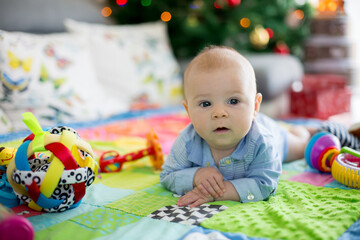Fototapeta na wymiar Happy three months old baby boy, playing at home on a colorful activity blanket