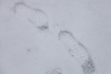 Two footprints inline in the white snow close up