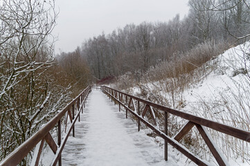 Winter landscape with a footbridge at the bottom of the ravine.