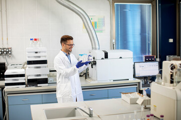 Young researcher workin with chemical samples in laboratory with HPLC system and  chromatography equipment