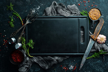 Black kitchen banner with board, spices and herbs. Top view. Free space for text.