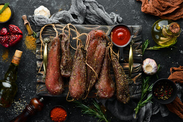 Dried salted chicken breast with rosemary and spices. Chicken meat. On a black stone background. Top view.