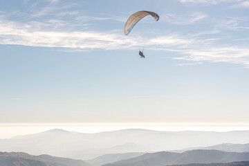 The paraglider is flying in the sky.