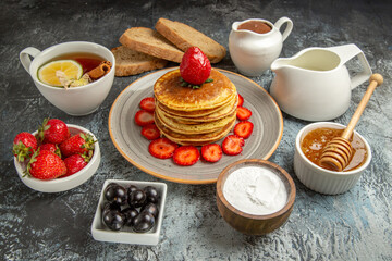 front view yummy pancakes with tea and fruits on a light background fruit cake sweet