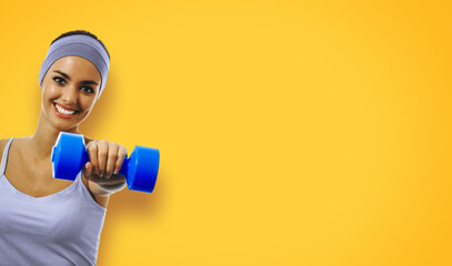 Happy smiling african american woman doing exercise with dumbbell, isolated on yellow color background. Sporty girl at studio shot. Health, beauty and fitness concept.