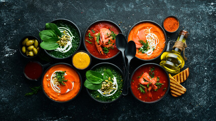 Fototapeta na wymiar Set of colored soups. Spinach soup, tomato cream soup and carrot puree soup. Healthy food. On a black stone background.