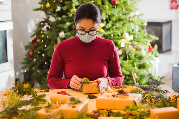 Young woman in medicine mask is packing zero waste gifts