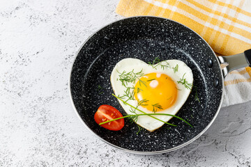 А heart shaped egg fried in a frying pan without oil