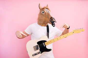 Man with horse mask pointing fingers at electric guitar