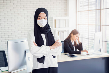 Multiethnic Asian muslim confident businesswoman worker wearing face mask health and safety COVID-19 working place cooperate business company, modern office background with coworker teamwork planning