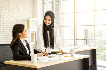 multiethnic asian female muslim working in office as team explaining and presenting in meeting to...