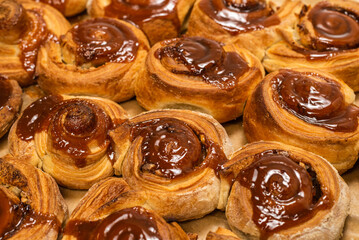 Homemade cinnamon buns with spices and caramel on parchment paper.