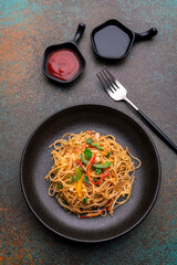 stir fried vegetarian noodles with sauce served in a black plate with fork