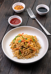stir fried vegetarian noodles with sauce served in a white plate with fork