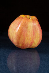 Red apple on turn blue table with reflection