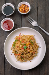stir fried vegetarian noodles with sauce served in a white plate with fork
