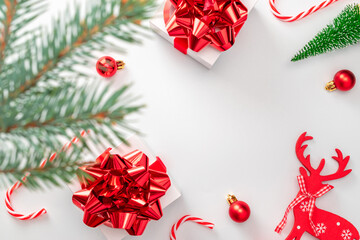 Winter background red. White gifts with scarlet bow, red balls, candy and winter tree in xmas decoration on white background for greeting card. Winter festive composition with copy space.