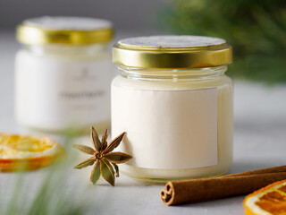 Aroma candle in a glass jar with the aroma of spices. The aroma of mulled wine. winter atmosphere with bokeh. winter scents. Star anise, cinnamon sticks, citrus fruits. 