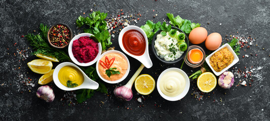 Set of sauces and spices on stone background. Sauces: mayonnaise, ketchup, tartare, barbecue and chili sauce in bowls. - obrazy, fototapety, plakaty