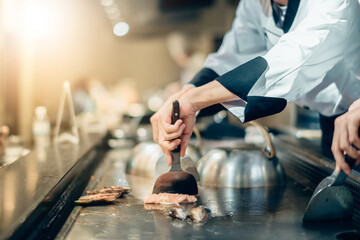 Hand of man take cooking of meat with vegetable grill, Chef cooking wagyu beef in Japanese teppanyaki restaurant
