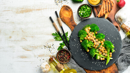 Healthy food: Broiled broccoli, chickpeas and sesame on a black stone plate. Top view. Free space for text.
