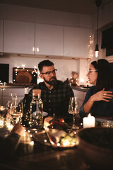 Two friends talking during a candlelit dinner party with friends
