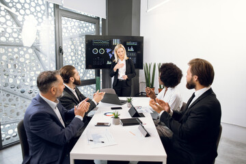 Pretty successful blond businesswoman gets congrats and cheers from her applauding multiethnic colleagues after project presentation. Promotion of career advance, joint teamwork and cooperation