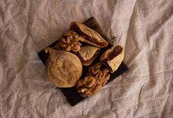 Vintage brown healthy food background, space for text. Dried figs, walnuts on the wooden plate, diet food, diet sugar, top view.