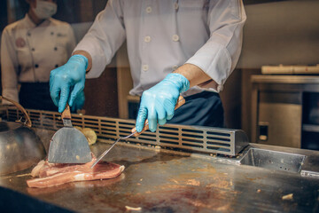 Hand of man take cooking of meat with vegetable grill, Chef cooking wagyu beef in Japanese teppanyaki restaurant
