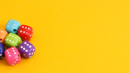 Small dice of various colors on yellow background.