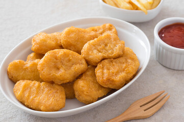 Chicken nuggets with potatoes chips and ketchup sauce.