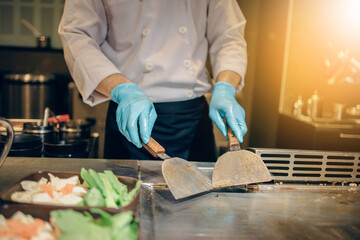 Hand of man take cooking of meat with vegetable grill, Chef cooking wagyu beef in Japanese teppanyaki restaurant