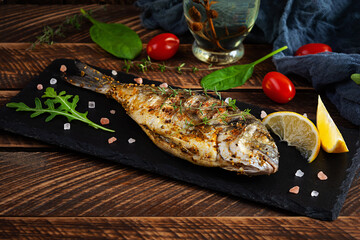 Grilled dorado fish on wooden background. Roasted seafish with spice and herbs