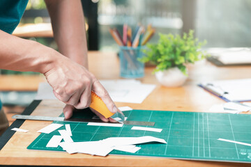 Developers use cutter to cut a mockup UX or UI paper on cutting mat.